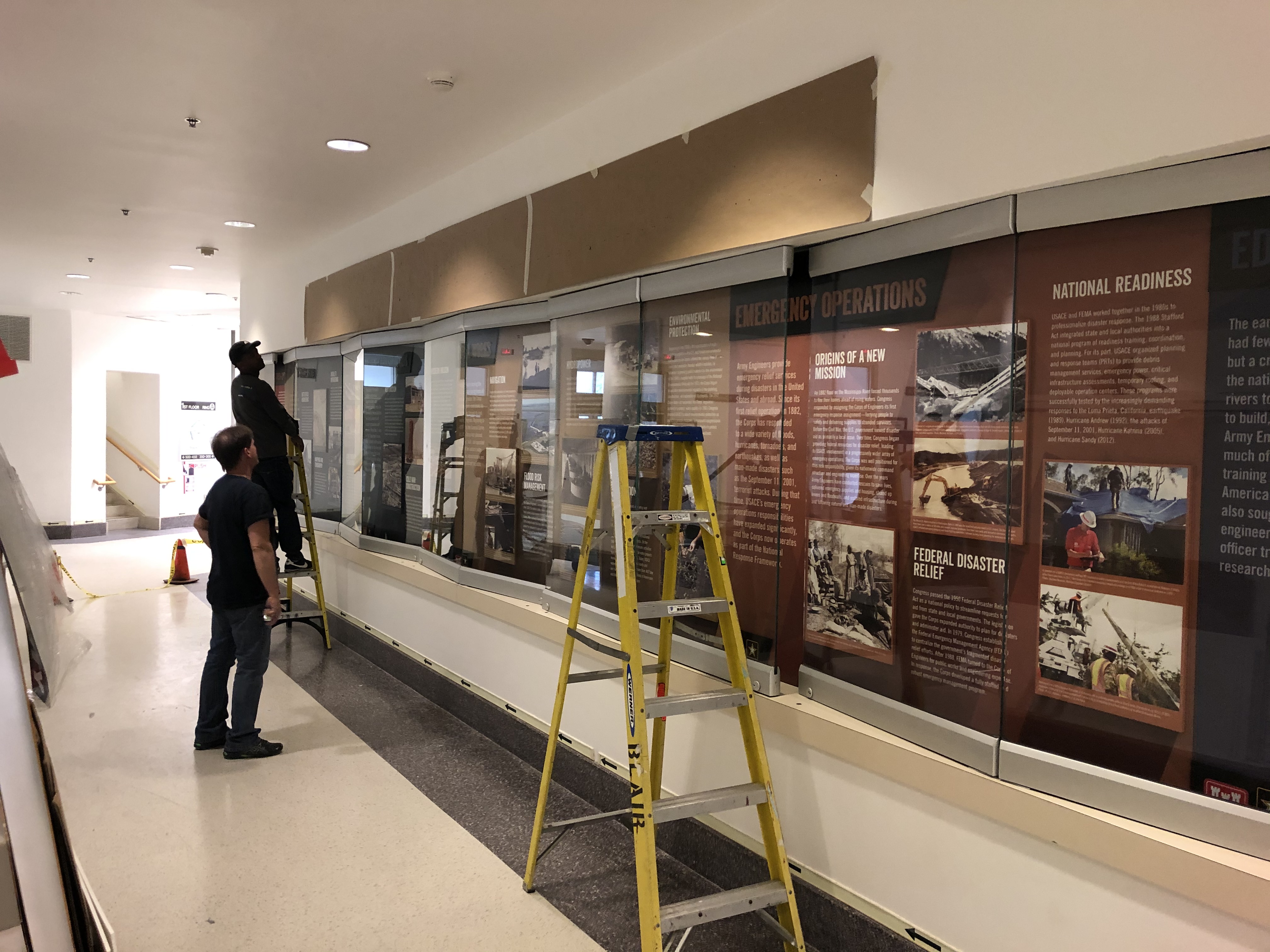 Men installing panels in wall cases with ladders